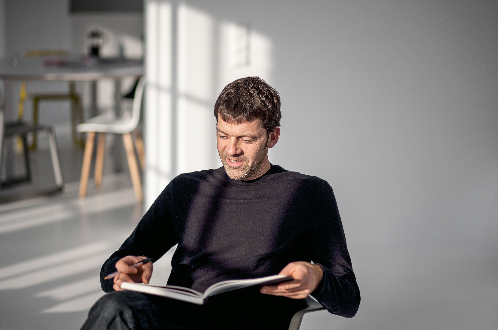 Dominik Tesseraux sitting on a chair looking into a notebook