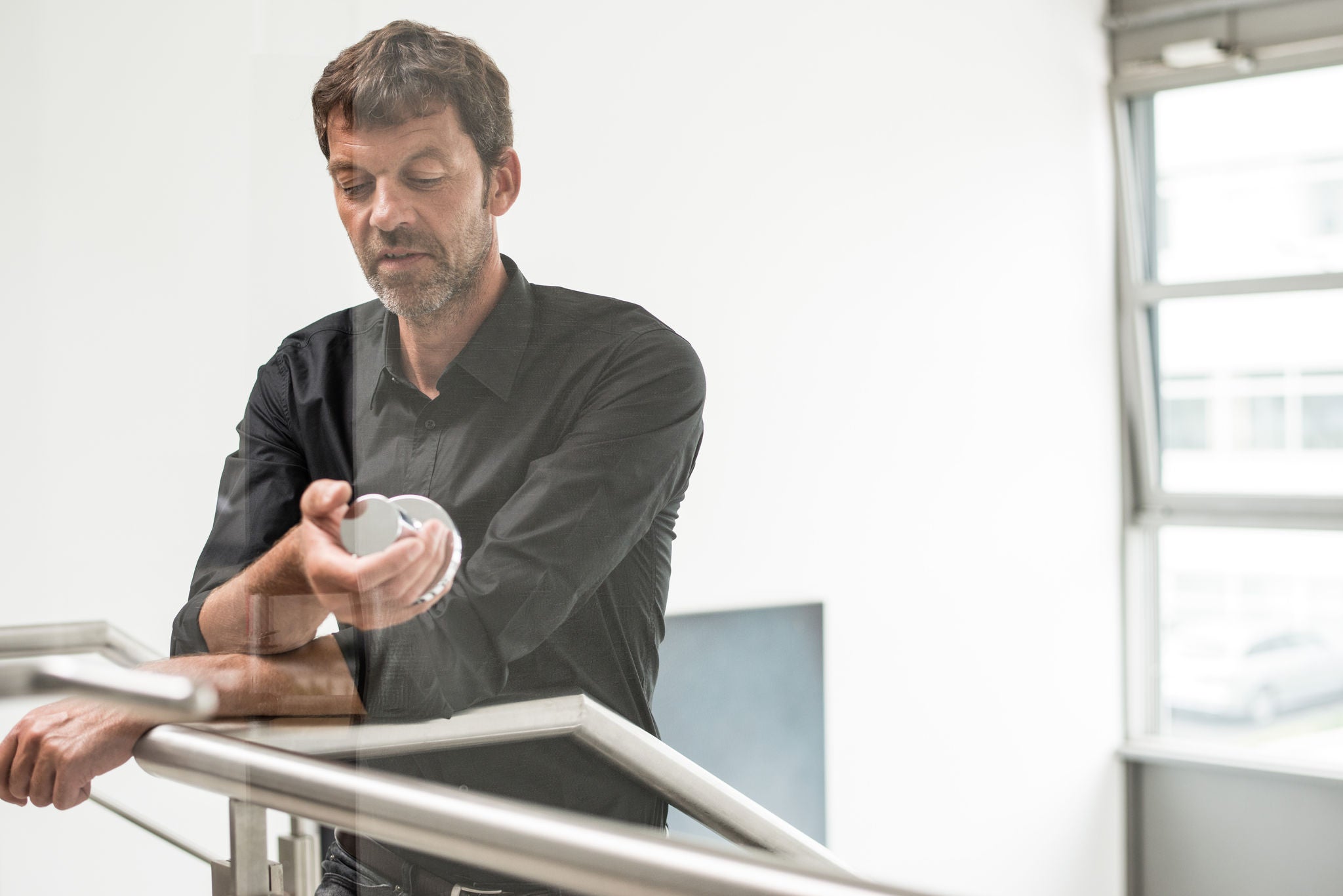 Dominik Tesseraux stands on a railing and holds an IXMO element in his hand