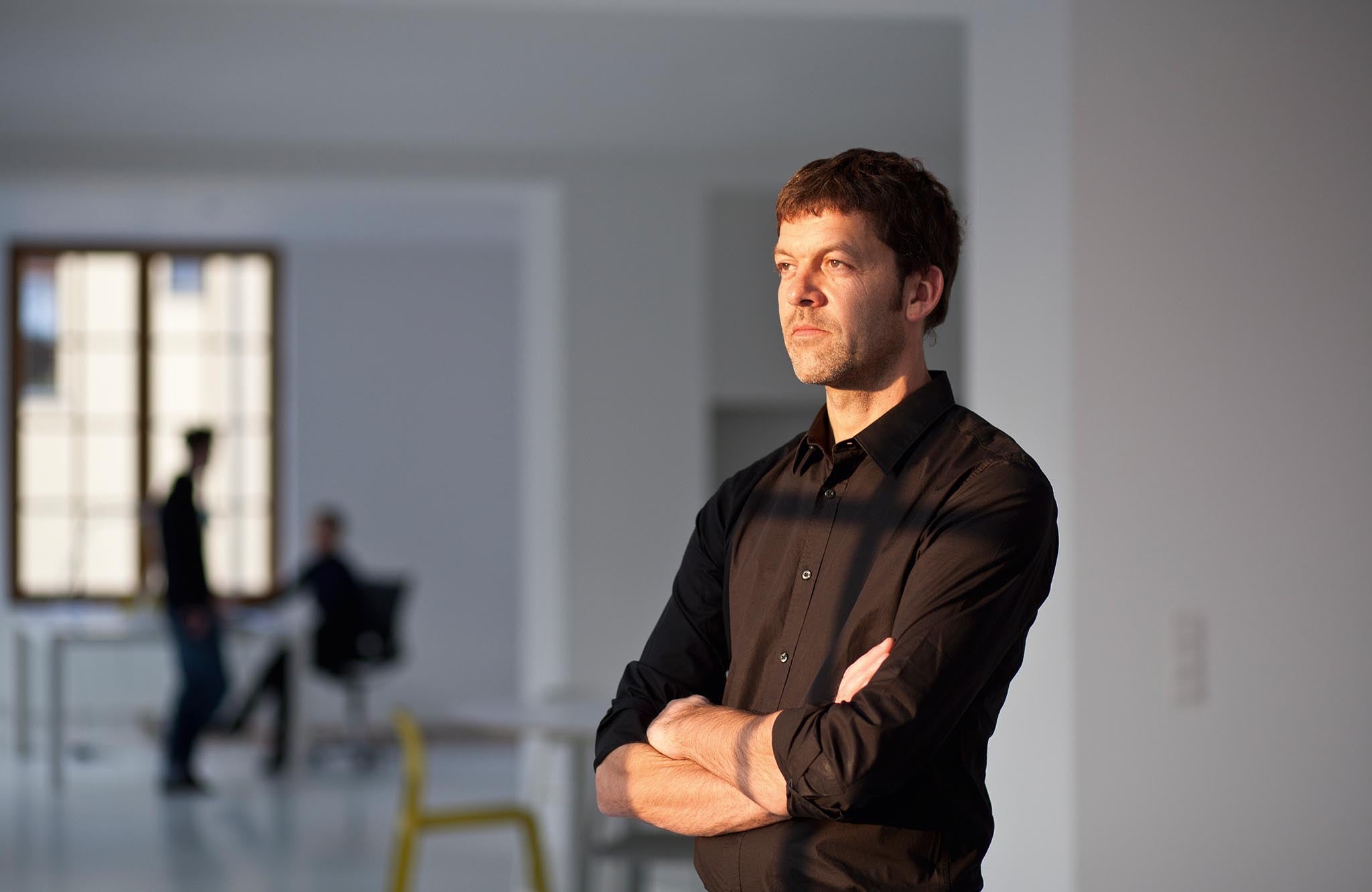 Dominik Tesseraux standing in the sunlight with arms crossed