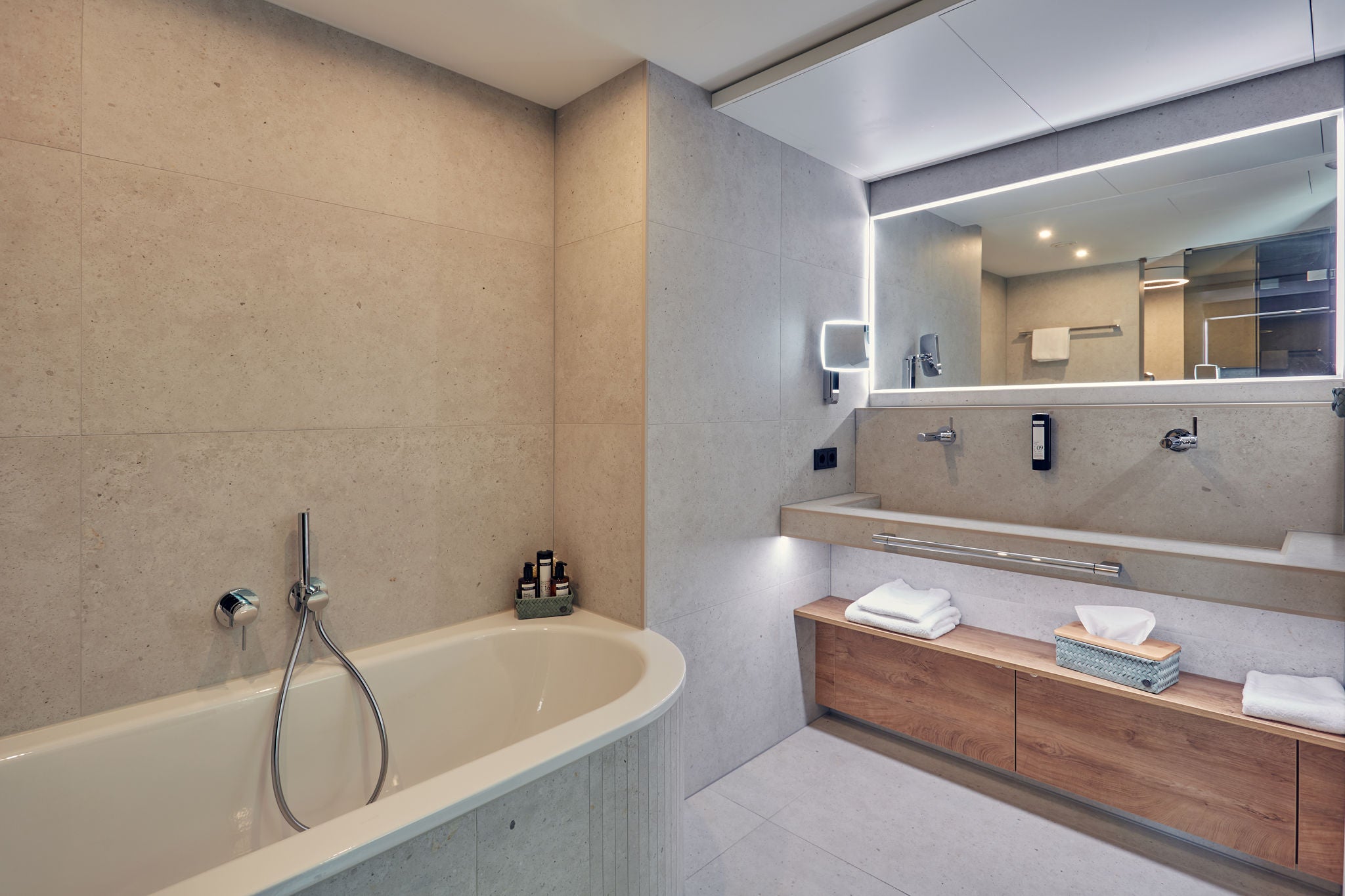 Bathtub and washing area in the Four Seasons Suite in Iserlohn with Shower luminaire with integrated shower heads and IXMO shower fittings as well as COLLECTION PLAN towel holder
