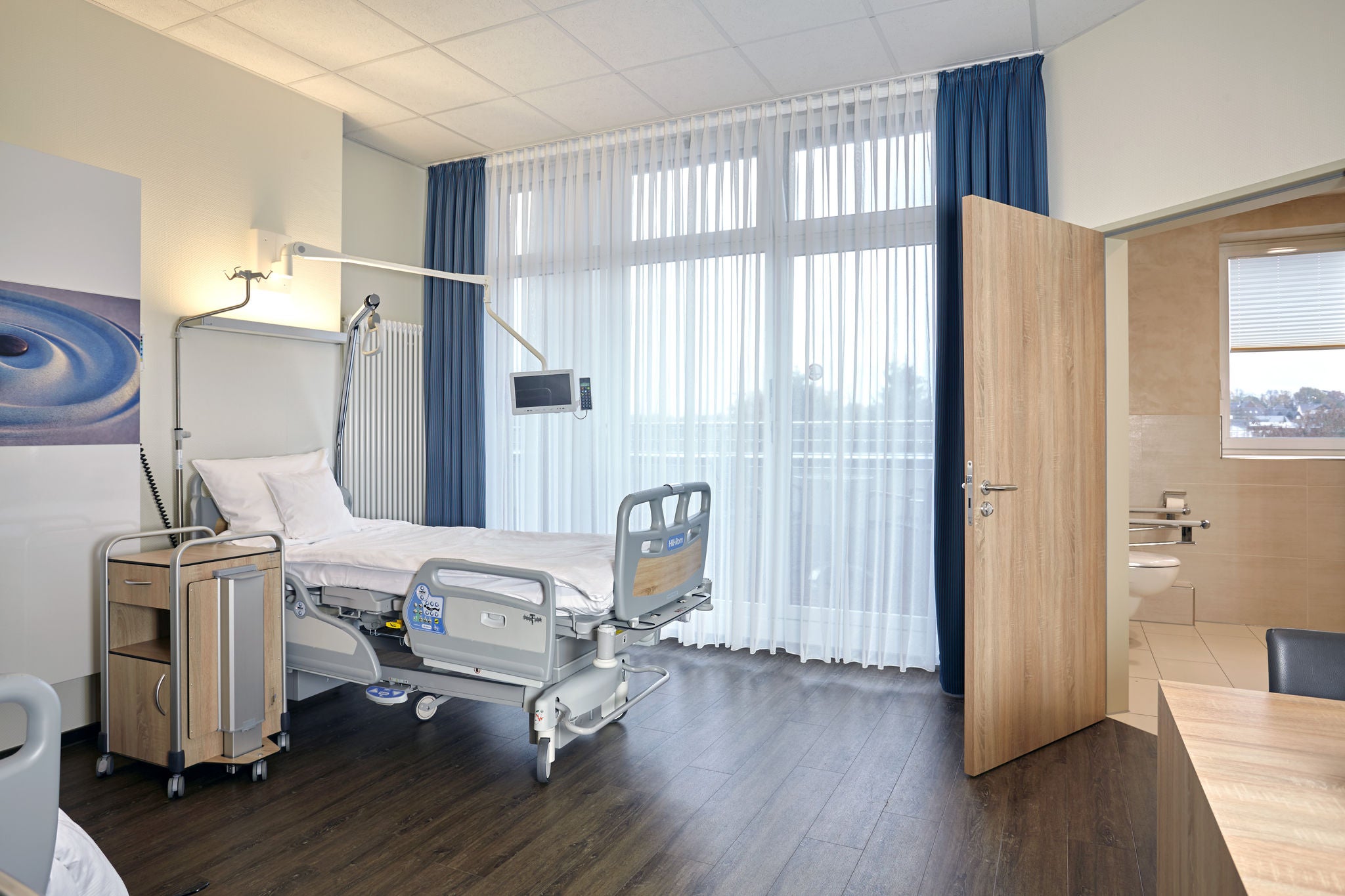Hospital room with view of the bathroom with KEUCO accessories on the toilet 